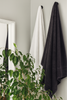 Two towels, one white and one dark gray, hanging on a rack with a plant in the foreground.