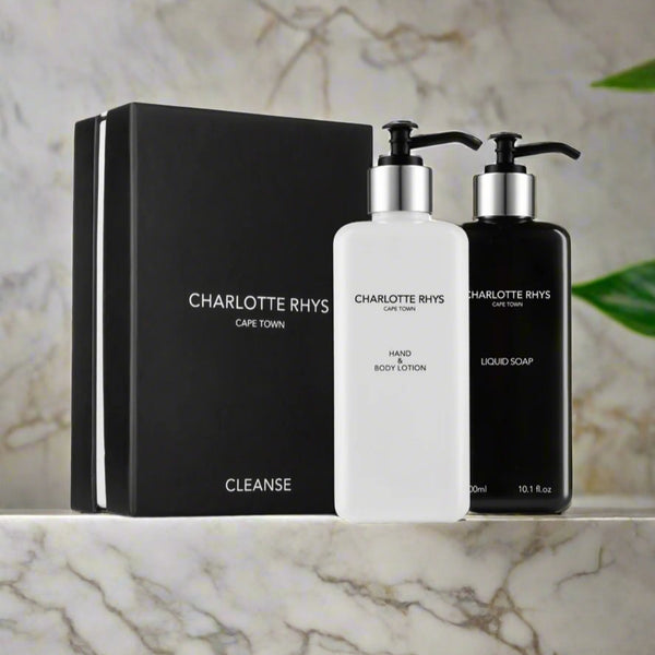 A gift set from Charlotte Rhys including a bottle of liquid soap and a pump bottle of body lotion, packaged in black and white bottles with a black box in the background.
