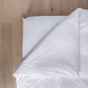 White comforter on a bed with wooden headboard
