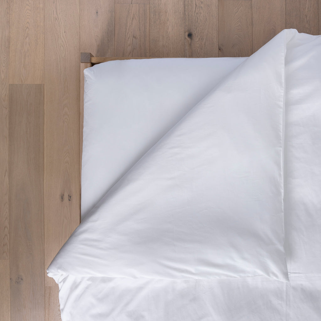 White comforter on a bed with wooden headboard