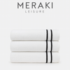 Stack of white towels with black stripes on a white background, featuring the Meraki Leisure logo.