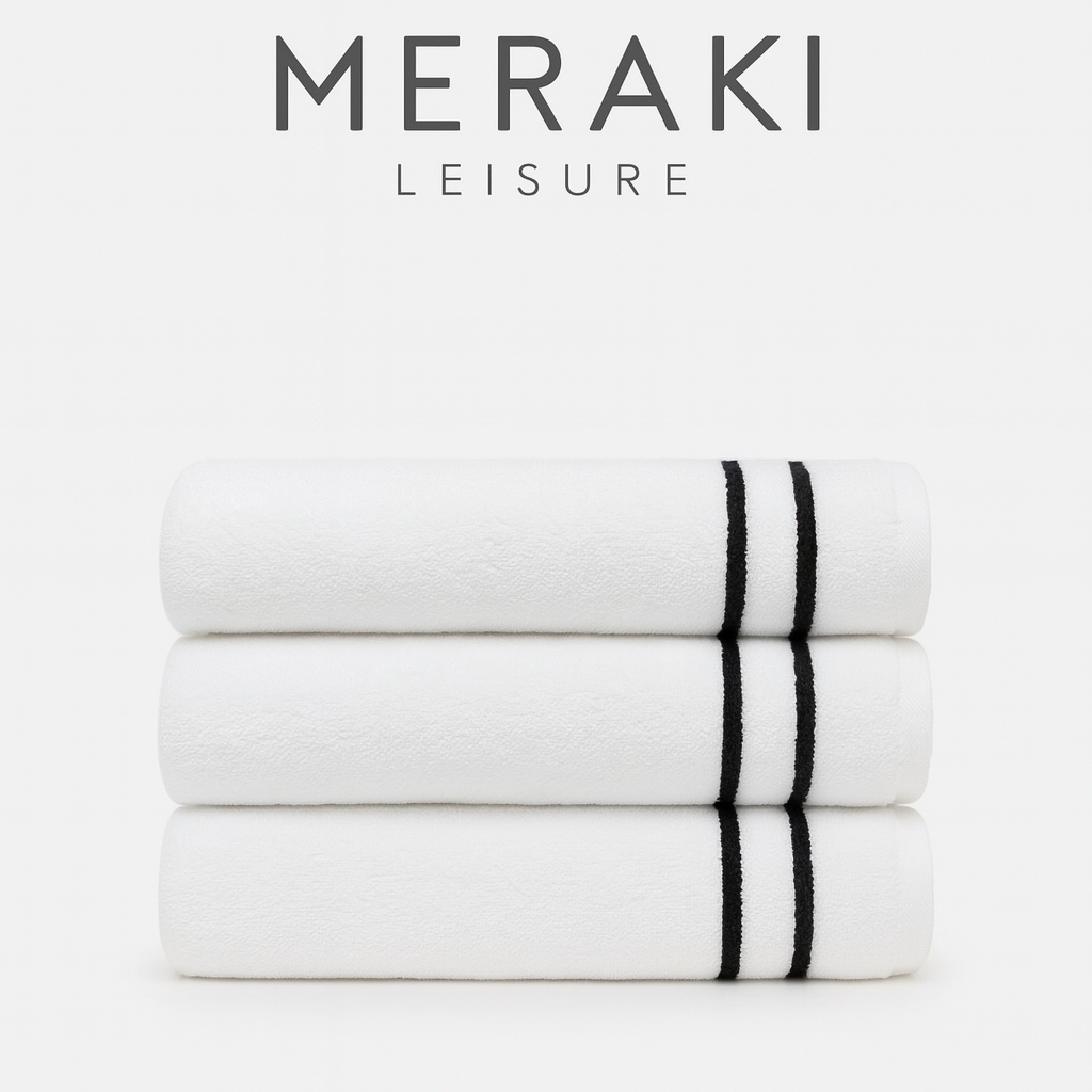 Stack of white towels with black stripes on a white background, featuring the Meraki Leisure logo.