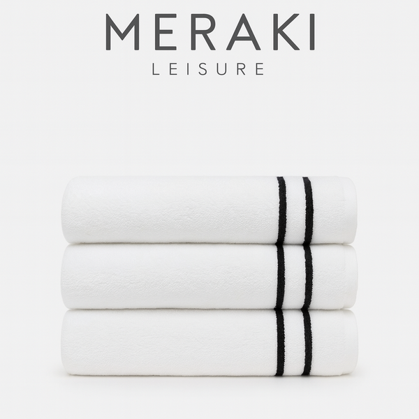 Stack of white towels with black stripes on a white background, featuring the Meraki Leisure logo.
